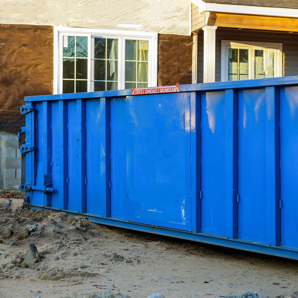 A large blue dumpster sits on a construction site